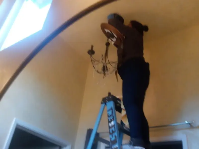 Electrician installing a chandelier in a Palm Valley residence